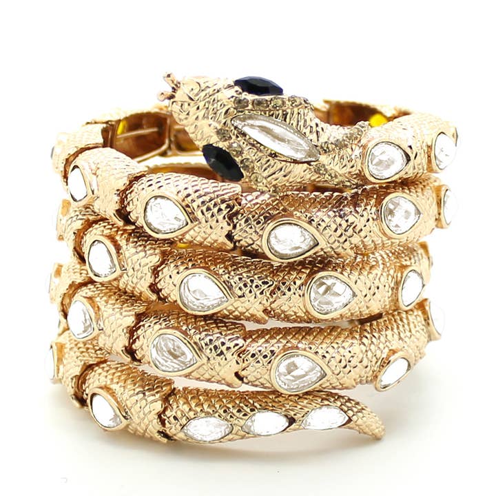 A gold cuff bracelet featuring a snake design with embellishments.